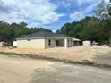 Newly constructed home with a neutral stucco exterior and covered patio in a wooded area at 3082 Se 140Th Ln, Summerfield, FL 34491