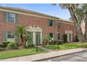 View of a brick townhouse featuring lush landscaping, green shutters, and classic architectural details at 316 Georgetown Dr # 316, Casselberry, FL 32707