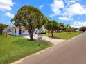 Well-maintained front yard with mature trees and landscaping leading to charming home at 413 5Th S St, Dundee, FL 33838