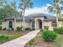 Stunning home exterior featuring a well-manicured lawn, palm trees, and a curved walkway to the front door at 502 Canopy Ln, Lady Lake, FL 32159