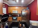 Functional kitchen featuring oak cabinetry, stainless steel appliances, and black countertops for a modern, efficient cooking space at 6335 Contessa Dr # 310, Orlando, FL 32829