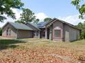 Side view of a one-story home featuring stucco walls, a green roof, solar panels and a red trim at 7045 Branch Ct, St Cloud, FL 34771