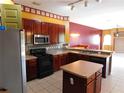 Well-lit kitchen featuring wood cabinets, stainless steel appliances, tile backsplash, and adjacent living areas at 7045 Branch Ct, St Cloud, FL 34771