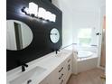 Modern bathroom featuring double sinks, sleek black fixtures, and a soaking tub at 10255 Cody Ln, Orlando, FL 32825