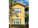 Close-up of a yellow apartment with a palm tree and manicured shrubbery at 12212 Wild Iris Way # 106, Orlando, FL 32837