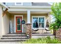 Inviting front porch with stone pillars, an orange front door, hanging chairs, and a 