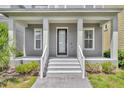 Inviting front porch with sturdy columns, fresh gray stairs, and a sleek black front door with house number at 13913 Hahn Ln, Orlando, FL 32827