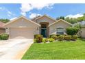 Inviting single-Gathering home with a manicured lawn, beige siding, and an attached two-car garage at 14155 Portrush Dr, Orlando, FL 32828
