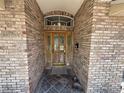 Close-up of the elegant front door with glass inserts and brick surround at 2120 Lakebreeze Way, Deltona, FL 32738