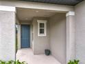Covered front porch with a blue front door, small window, and pot for flowers at 2241 Mystic Maze Ln, Minneola, FL 34715