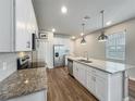 Modern kitchen with stainless steel appliances, white cabinetry, granite countertops and wood flooring at 2241 Mystic Maze Ln, Minneola, FL 34715