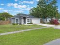 Landscaped front yard with green grass leading to a charming gray single-story home with an attached garage at 2755 Abbey Ave, Orlando, FL 32833
