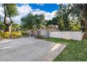 A gray home featuring a spacious driveway and an adjacent white fence at 3049 Condel Drive, Orlando, FL 32812