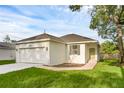 Single-story home with a two-car garage, fresh landscaping, and a sidewalk leading to the front door at 31830 Sybil Ave, Sorrento, FL 32776