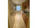 Efficient kitchen with tile flooring, wood cabinetry, laminate countertops and white refrigerator at 440 Martigues Dr, Kissimmee, FL 34759