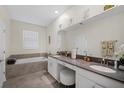 Bright bathroom featuring dual sinks, a vanity, a soaking tub, and a large mirror at 8907 Fallen Oak, Davenport, FL 33897