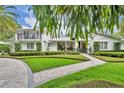 Attractive two-story home showcasing manicured landscaping, balcony, and curved brick path at 940 Lincoln Cir, Winter Park, FL 32789