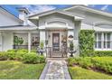 Charming home entrance featuring manicured shrubs, a brick pathway, and covered porch at 940 Lincoln Cir, Winter Park, FL 32789