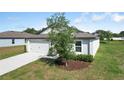 Single Gathering home boasts a tidy lawn, two-car garage and fresh landscaping, adding to its curb appeal at 1119 Union Ave, Mascotte, FL 34753