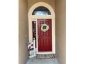 A welcoming red front door adorned with a white flower wreath and 'Welcome' sign, inviting you into this charming home at 1585 Stefan Cole Ln, Apopka, FL 32703