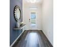 Bright foyer featuring hardwood floors, a decorative mirror, and a view of the front door at 1974 Walnut Creek Dr, Kissimmee, FL 34744