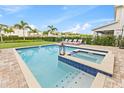 Sparkling pool and spa with a brick patio, lounge chairs, and lush landscaping at 257 Auburn Ave, Kissimmee, FL 34747