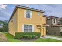 Charming two-story home with a yellow exterior, white trim, and a neatly landscaped front yard at 2999 Buccaneer Palm Rd, Kissimmee, FL 34747