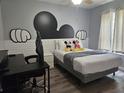Playful bedroom with grey walls, wood floors, Mickey Mouse accents, and a comfortable bed at 3193 Yellow Lantana Ln, Kissimmee, FL 34747