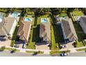 Aerial view of a home with a well-manicured lawn, mature trees, and neighborhood pools at 341 Falls Dr, Kissimmee, FL 34747