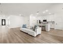 Open-concept living room and kitchen area, showcasing contemporary design and wood floors at 3981 Great Smokey Way, Apopka, FL 32712