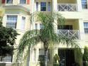 Close-up of a condo building showing the architecture, windows, balconies, and a mature palm tree in the front at 5276 Cane Island Loop # 302, Kissimmee, FL 34746