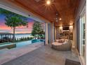 Covered patio boasts an outdoor kitchen and cozy seating area next to a sparkling pool and serene lake view at 9916 Lone Tree Ln, Orlando, FL 32836