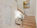 Bright foyer with modern staircase, mirrored chest, stylish light fixture, and decorative artwork at 10371 Kensington Shore Dr # H-201, Orlando, FL 32827