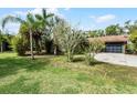 Image of the green home with a well-manicured lawn, mature trees, and a long driveway leading to the garage at 1200 Auger Dr, New Smyrna Beach, FL 32168