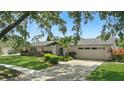 Inviting one-story home boasts lush landscaping, a brick facade, and a spacious driveway leading to a garage at 2756 Summerfield Rd, Winter Park, FL 32792