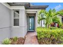 Close up of the front entrance with blue-green door, manicured landscaping, and a brick pathway at 3149 Songbird Cir, Harmony, FL 34773