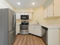 Well-lit kitchen with stainless steel appliances, white cabinets, and wood-look flooring at 4652 Oak Arbor Cir, Orlando, FL 32808