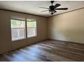 A sunlit bedroom with wood-look flooring, two windows, neutral walls, and an overhead fan at 56048 Blue Creek Rd, Astor, FL 32102