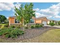 View of the front yard with a tree, shrubs and mulch, as well as the house, which is stucco with stone facade at 8932 Sw 101St Cir, Ocala, FL 34481