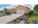 Exterior view of the property showcasing a concrete driveway leading to an attached two-car garage and manicured landscaping at 8932 Sw 101St Cir, Ocala, FL 34481