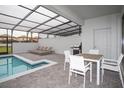 Outdoor patio with dining table, lounge chairs, and a screened-in private pool at 8944 Sydney Ave, Kissimmee, FL 34747
