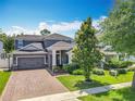 Two-story home with a brick driveway, a grey exterior, mature trees and a neatly landscaped front yard at 1086 Calla Lily Cv, Oviedo, FL 32766