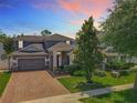 Two-story home with a brick driveway, a grey exterior, mature trees and a neatly landscaped front yard at 1086 Calla Lily Cv, Oviedo, FL 32766