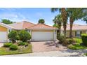 Beautiful single-story home featuring a red tile roof, lush landscaping, and a brick-paved driveway at 11863 Delfina Ln, Orlando, FL 32827