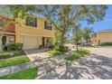 Exterior view of a two-story yellow townhome with an attached garage and lush front lawn at 13480 Applerose Ln # 19, Orlando, FL 32824
