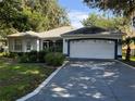 Charming single-story home with a gray driveway, a two-car garage, and landscaped front yard at 144 Costa Mesa Dr, Lady Lake, FL 32159