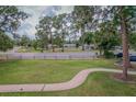 A sidewalk leads to a charming park-like setting with mature trees and a well-maintained lawn at 1505 W Lake Cannon Nw Dr, Winter Haven, FL 33881
