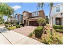 Attractive two-story home featuring a brick-paved driveway, manicured landscaping, and a two-car garage at 480 Lasso Dr, Kissimmee, FL 34747