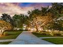 Sprawling front yard with mature trees, lush landscaping and elegant exterior lighting at 5025 Down Point Ln, Windermere, FL 34786