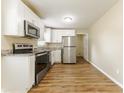 Clean kitchen featuring white cabinets, stainless steel appliances, granite countertops and wood-look floors at 5822 Flori Ln, Orlando, FL 32808